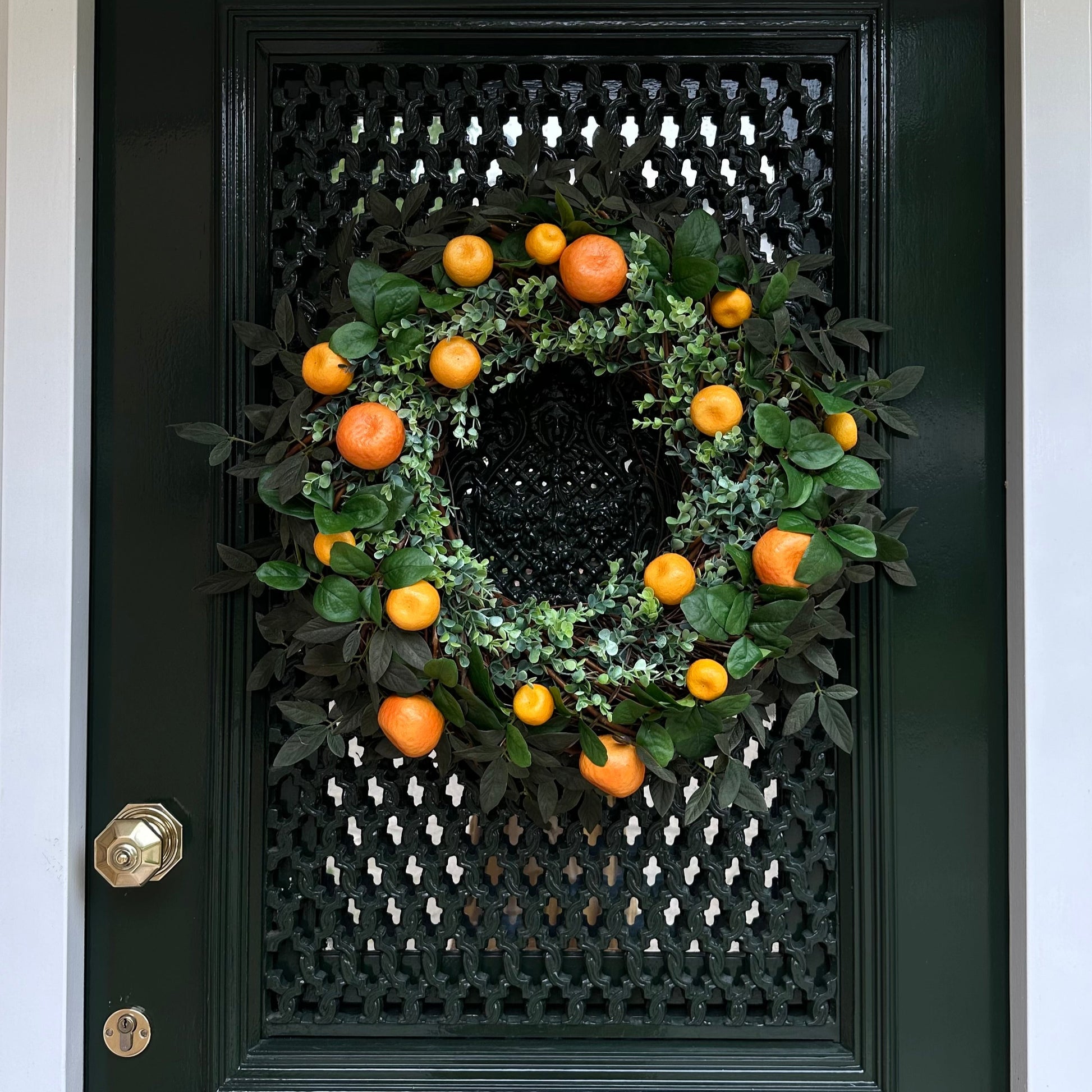 Handgemaakte luxe deurkrans met kunstmatige mandarijnen, sinaasappels en levendig groen eucalyptusblad, zorgvuldig gerangschikt op een natuurlijke takkenbasis. Deze mediterrane krans van Jardin Enchanté brengt een zomerse, zonnige sfeer en straalt elegantie en frisheid uit. Perfect als luxe kunstbloemenkrans voor de voordeur of interieurdecoratie, ideaal voor liefhebbers van stijlvolle, exclusieve seizoensdecoratie. De vrolijke citrusaccenten geven een warm, uitnodigend en verfijnd karakter aan je huis en c