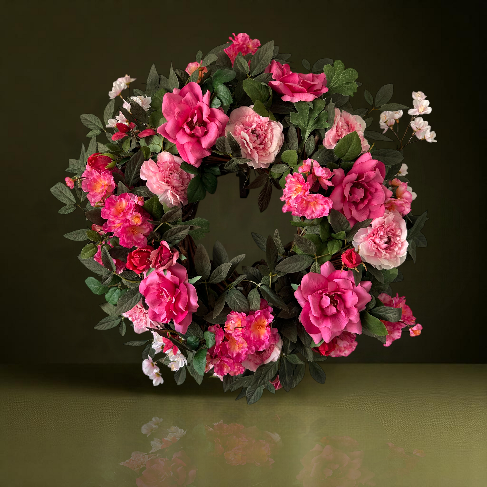 Handgemaakte luxe deurkrans met roze en fuchsia kunstrozen, pioenrozen en ranonkels op een groene, natuurlijke ondergrond — Jardin Enchanté.