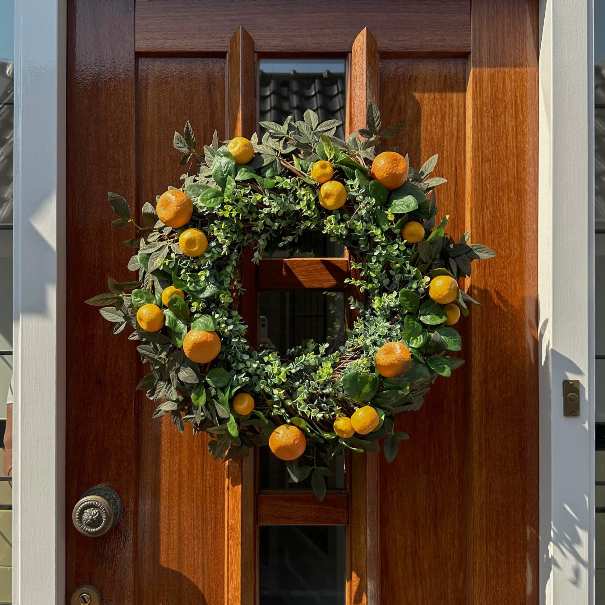 Handgemaakte luxe deurkrans met kunstmatige mandarijnen, sinaasappels en levendig groen eucalyptusblad, zorgvuldig gerangschikt op een natuurlijke takkenbasis. Deze mediterrane krans van Jardin Enchanté brengt een zomerse, zonnige sfeer en straalt elegantie en frisheid uit. Perfect als luxe kunstbloemenkrans voor de voordeur of interieurdecoratie, ideaal voor liefhebbers van stijlvolle, exclusieve seizoensdecoratie. De vrolijke citrusaccenten geven een warm, uitnodigend en verfijnd karakter aan je huis en c