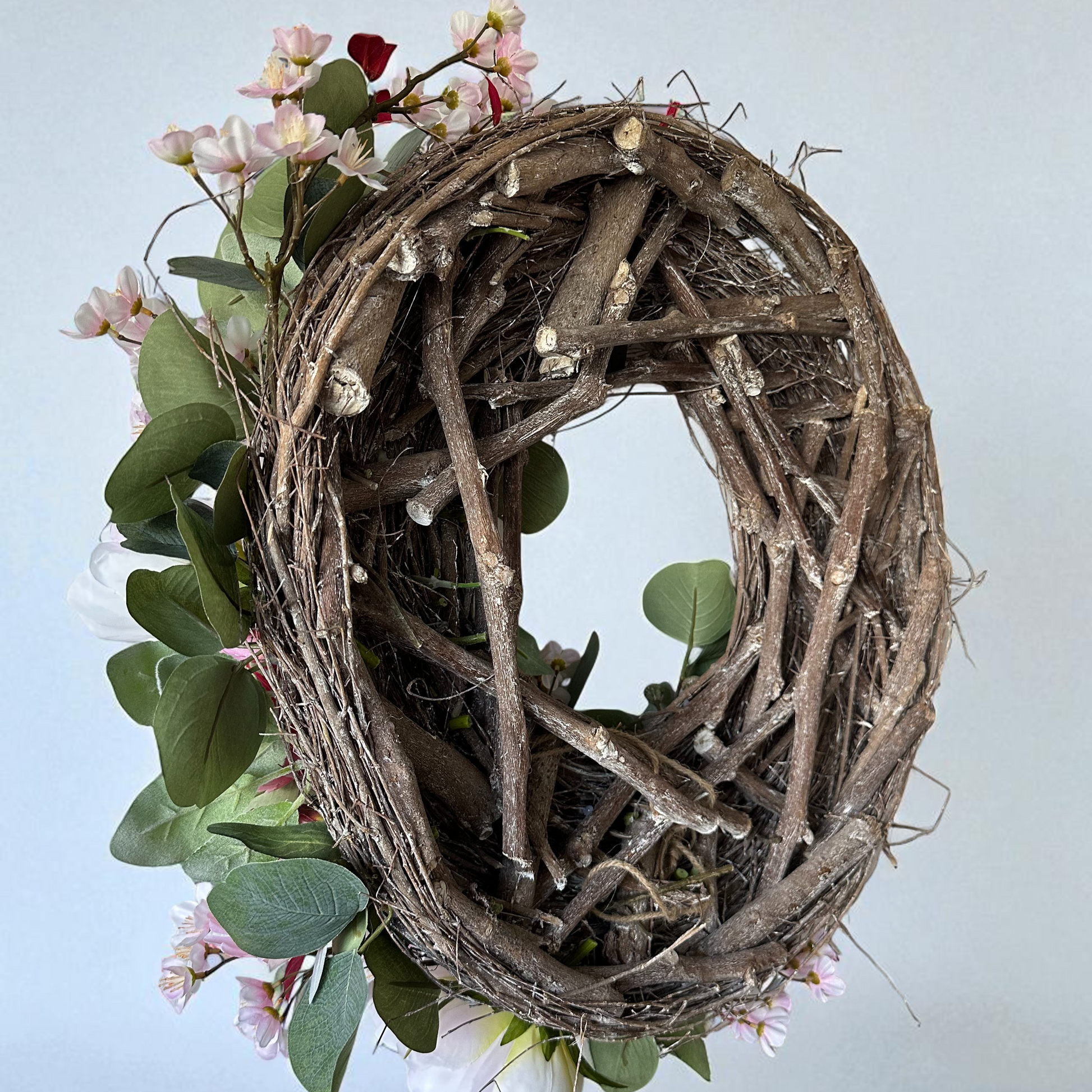 Handgemaakte luxe deurkrans met zijden pioenrozen in zachte blushroze en crèmekleurige tinten, gecombineerd met kunst kersenbloesems en fluweelachtig groen blad, zorgvuldig gerangschikt op een natuurlijke takkenbasis. Deze romantische, asymmetrische bloemenkrans van Jardin Enchanté straalt Franse elegantie en verfijnde charme uit. Perfect als luxe kunstbloemenkrans voor de voordeur, muurdecoratie of feestelijke gelegenheid, en ideaal voor liefhebbers van romantische, exclusieve seizoensdecoratie.