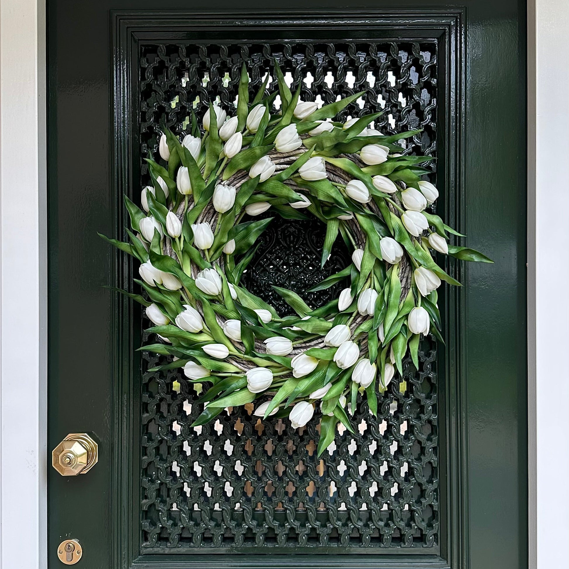 Handgemaakte luxe deurkrans met elegante witte kunsttulpen, zorgvuldig gerangschikt op een natuurlijke gevlochten basis van takken, perfect voor een stijlvolle voordeurdecoratie of als muurdecoratie binnenshuis. Deze exclusieve tulpenkrans van Jardin Enchanté straalt tijdloze verfijning en een romantische, frisse uitstraling uit. Ideaal voor wie op zoek is naar een bijzondere seizoensdecoratie, lente- of zomerkrans, of luxe kunstbloemen krans voor een warm en uitnodigend huis.