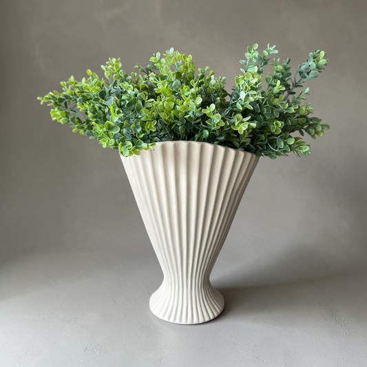 Fresh Greenery Boeket, een luxe zijden boxwood boeket met realistische groene takken in een witte geribbelde vaas op een stenen tafel in warm natuurlijk licht