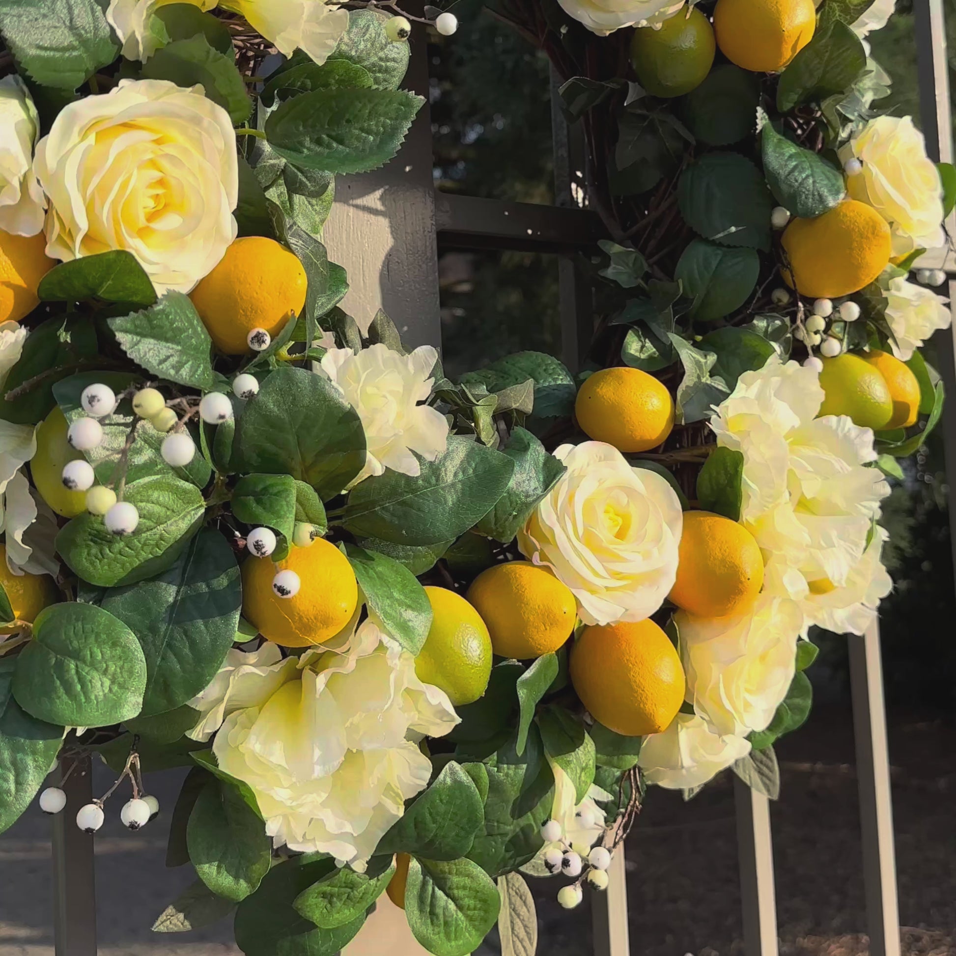 Handgemaakte luxe deurkrans van Jardin Enchanté met elegante zachtgele kunstrozen, speelse citroenen, delicate witte bessen en weelderig groene bladeren op een natuurlijke basis. Deze stijlvolle krans brengt een frisse mediterrane uitstraling en zonnige charme naar elke deur of muur en is perfect als zomerse decoratie voor een warm en uitnodigend huis.