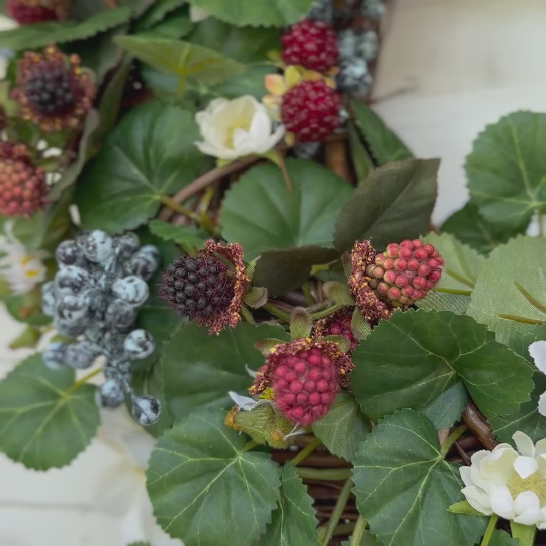 Handgemaakte luxe deurkrans met kunstzwarte bessen, frambozen, blauwe bessen, witte bloemen en rijk groen blad, kunstig gerangschikt op een natuurlijke, gevlochten takkenbasis. Deze betoverende boskrans van Jardin Enchanté brengt een elegante, wilde en sprookjesachtige uitstraling aan je voordeur of interieur. Perfect als seizoensdecoratie voor zomer en herfst, en ideaal voor liefhebbers van luxe kunstbloemenkransen en exclusieve deurdecoraties. Deze natuur geïnspireerde krans creëert een warme, poëtische s