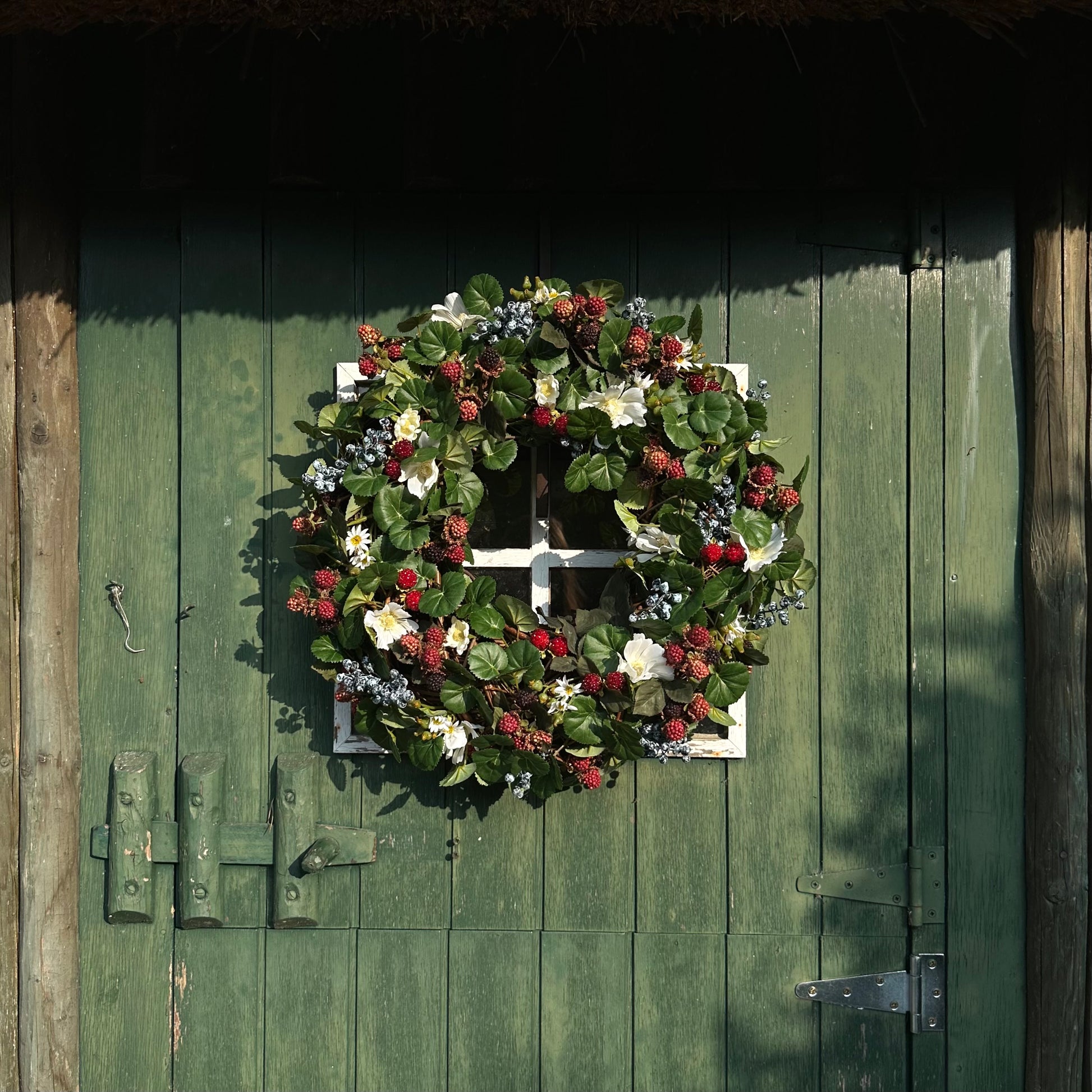 Handgemaakte luxe deurkrans met kunstzwarte bessen, frambozen, blauwe bessen, witte bloemen en rijk groen blad, kunstig gerangschikt op een natuurlijke, gevlochten takkenbasis. Deze betoverende boskrans van Jardin Enchanté brengt een elegante, wilde en sprookjesachtige uitstraling aan je voordeur of interieur. Perfect als seizoensdecoratie voor zomer en herfst, en ideaal voor liefhebbers van luxe kunstbloemenkransen en exclusieve deurdecoraties. Deze natuur geïnspireerde krans creëert een warme, poëtische s