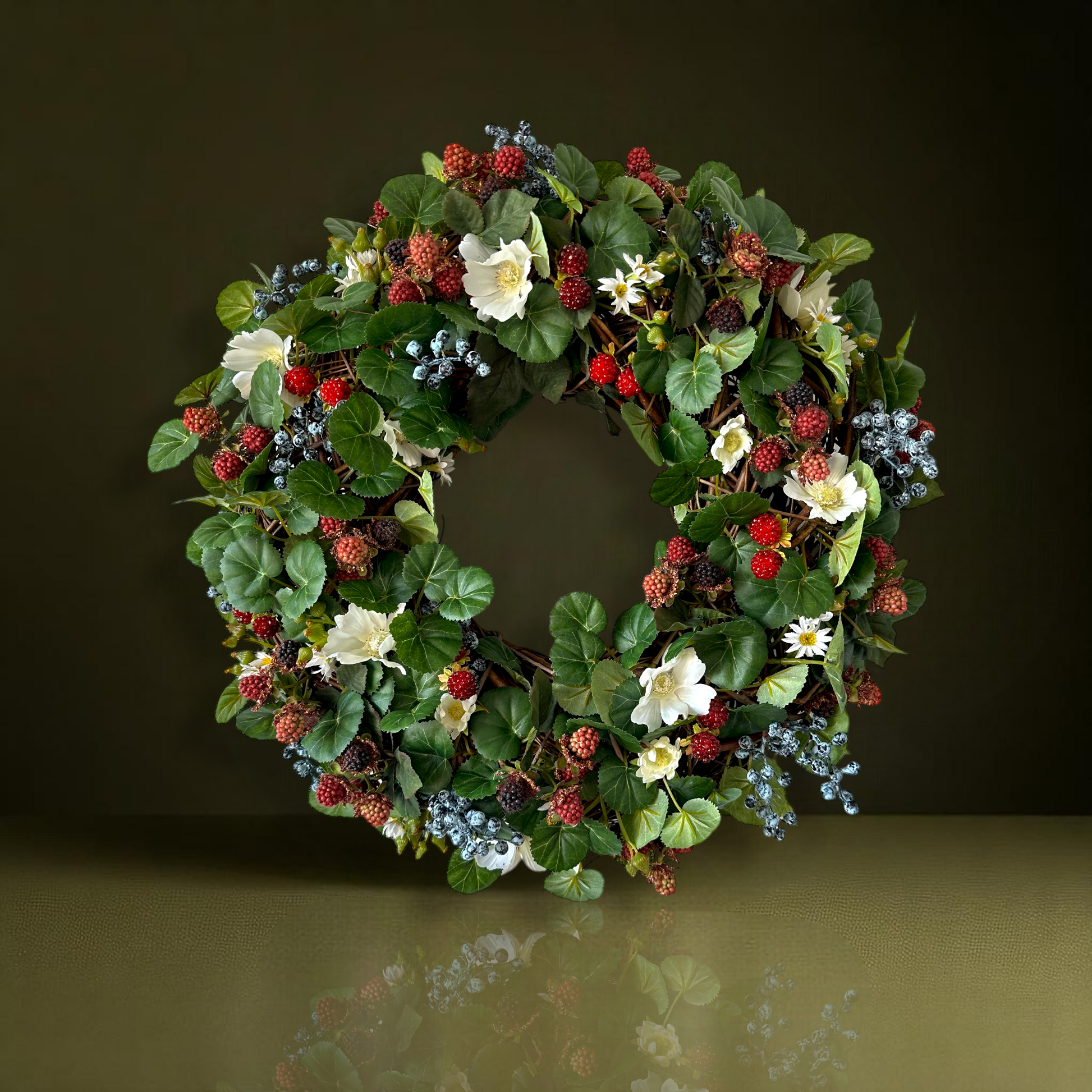 Handgemaakte luxe deurkrans met kunstzwarte bessen, frambozen, blauwe bessen, witte bloemen en rijk groen blad, kunstig gerangschikt op een natuurlijke, gevlochten takkenbasis. Deze betoverende boskrans van Jardin Enchanté brengt een elegante, wilde en sprookjesachtige uitstraling aan je voordeur of interieur. Perfect als seizoensdecoratie voor zomer en herfst, en ideaal voor liefhebbers van luxe kunstbloemenkransen en exclusieve deurdecoraties. Deze natuur geïnspireerde krans creëert een warme, poëtische s