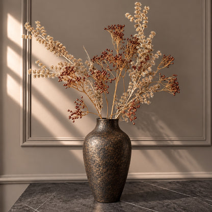 EN: Luxury faux botanical arrangement featuring copper berry branches and champagne-coloured foliage in a dark bronze vase. NL: Luxe kunstbloemenarrangement met koperkleurige bessentakken en champagnekleurige siertakken in een donkerbronzen vaas.