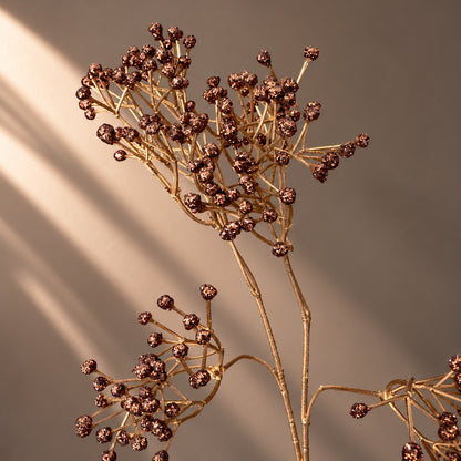 EN: Close-up of artificial copper berry branch with textured metallic bronze berries and delicate golden stems. NL: Detail van kunsttak met koperkleurige metallic bessen en fijne goudkleurige stelen.