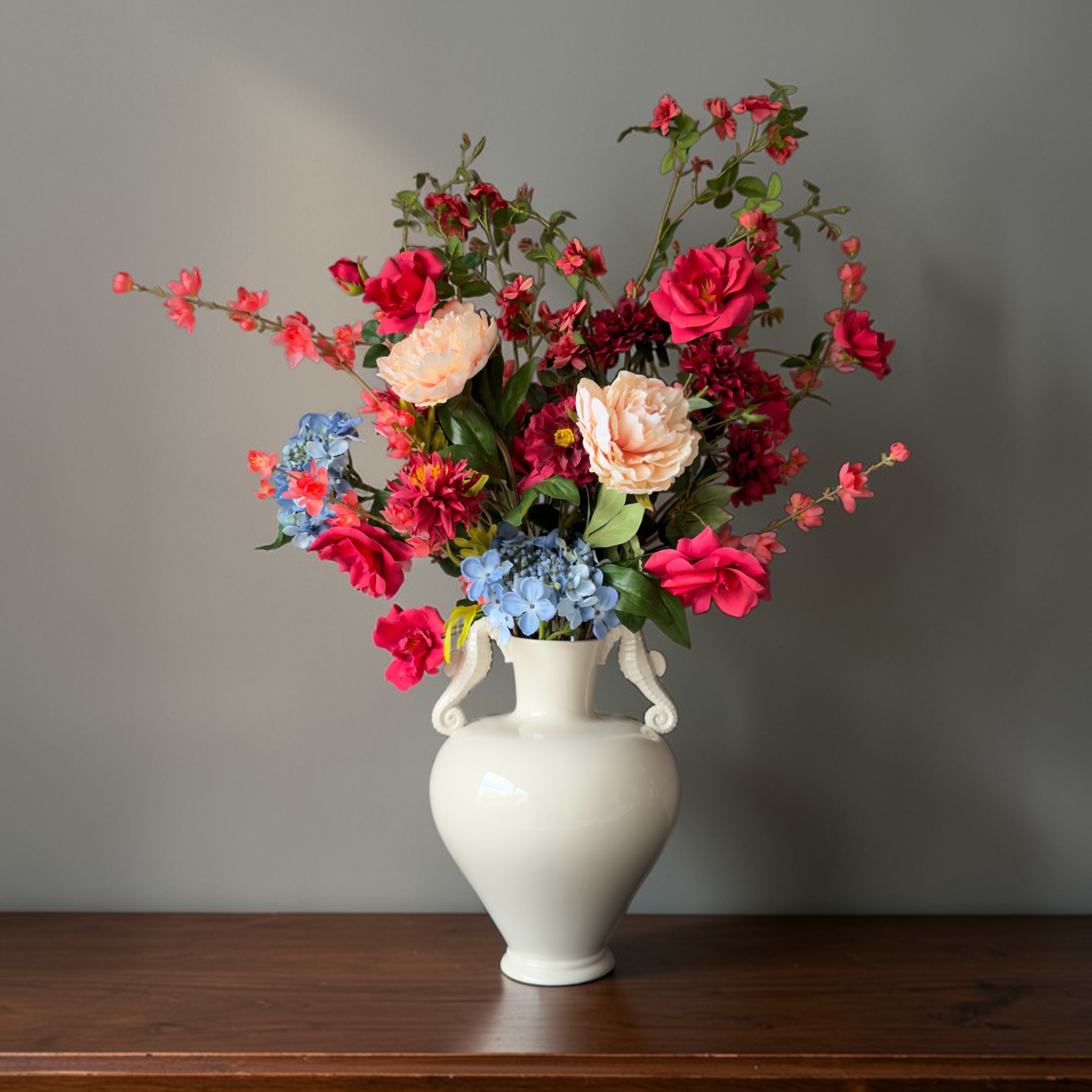 Coral Garden Bouquet with high-quality silk flowers in coral, red, blush and blue tones styled in a white ceramic vase for elegant home decor
