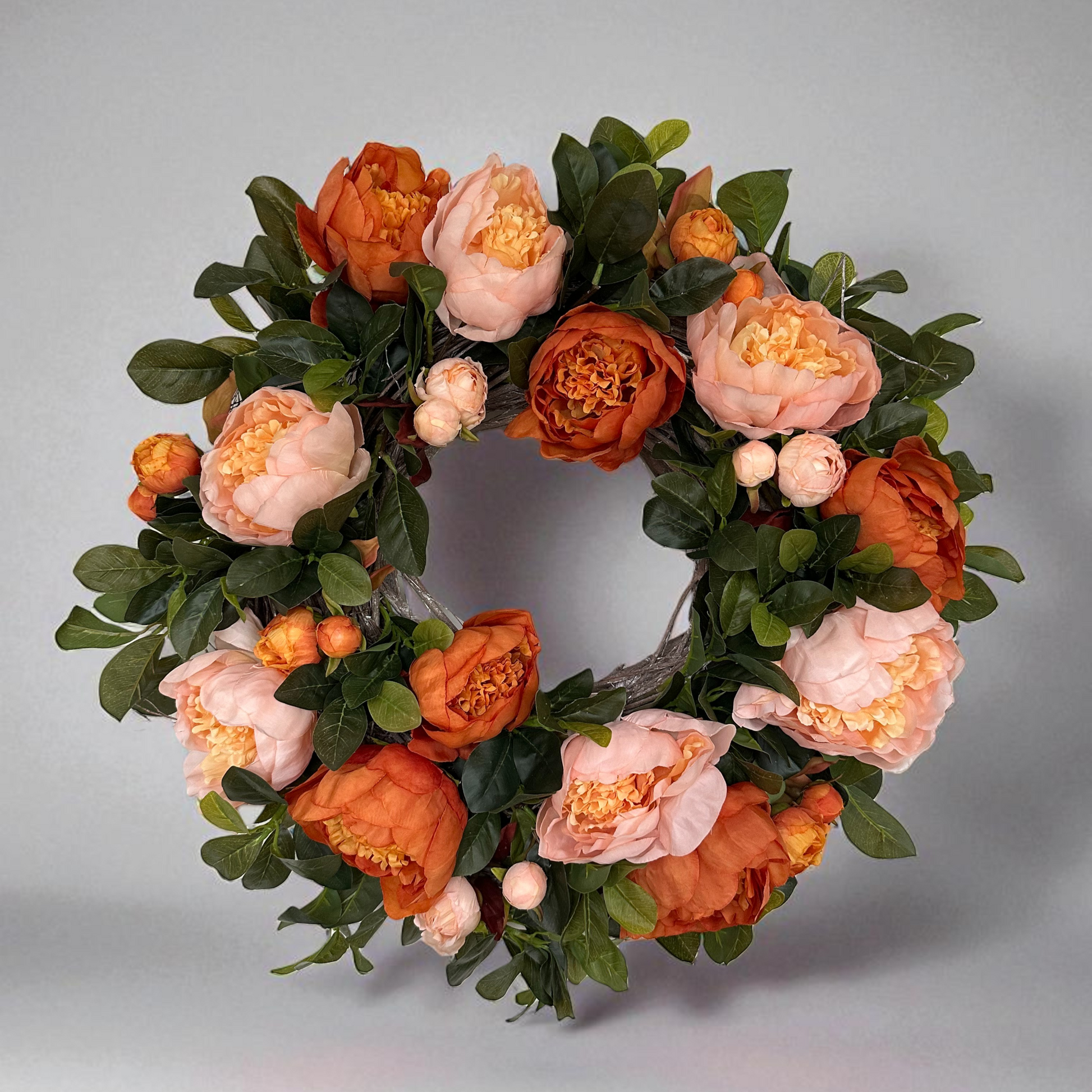 Handmade floral wreath with peach and burnt orange peonies, accented with lush green foliage. Elegant seasonal wreath perfect for front door décor, weddings, or home decoration – a timeless statement piece with romantic autumn tones.