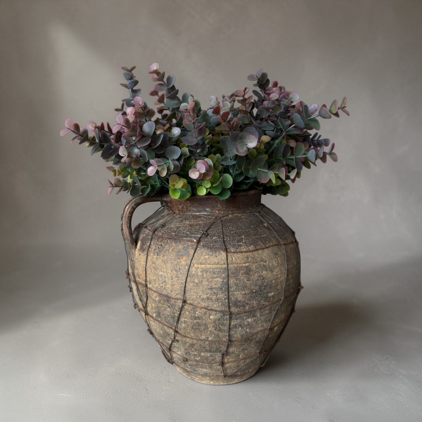 Dusky Eucalyptus Bouquet with high-quality silk eucalyptus stems in muted green and soft burgundy tones styled in a rustic vase for elegant home decor