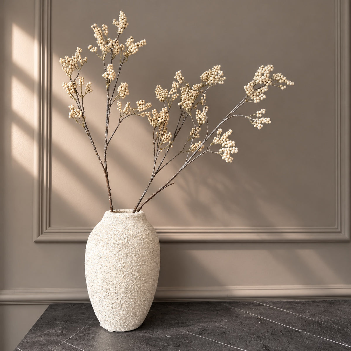 Frosted cream berry branches in a textured ivory vase against a taupe panelled wall, winter artificial botanical arrangement | Kunsttakken met crèmekleurige besjes in vaas, winterdecoratie