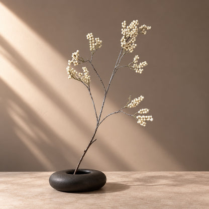 Single frosted cream berry stem with ivory berries in a low black vase, minimalist Christmas decor | Kunst bessentak met witte besjes in zwarte vaas, kerstdecoratie
