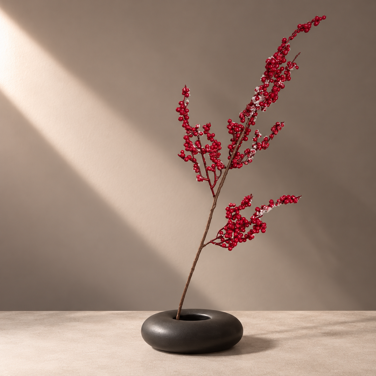 Frosted red berry faux branch displayed in a matte black flat vase