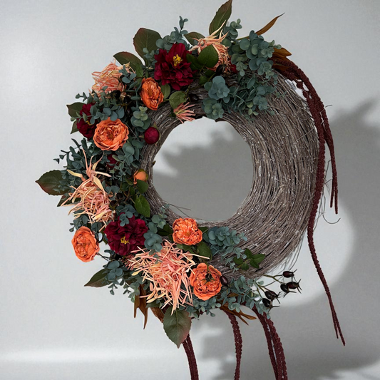Elegant Falling Roses Wreath with orange roses, burgundy blooms, eucalyptus, and wilted spider mum flowers on a rustic twig base