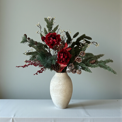Luxe winterboeket met rode pioenrozen, dennentakken en dennenappels, handgemaakt door Jardin Enchanté. Elegant kunstbloemen boeket voor kerst en winterdecoratie, met natuurlijke uitstraling en warme seizoenskleuren. Perfect voor stijlvolle interieurdecoratie of als feestelijk cadeau.