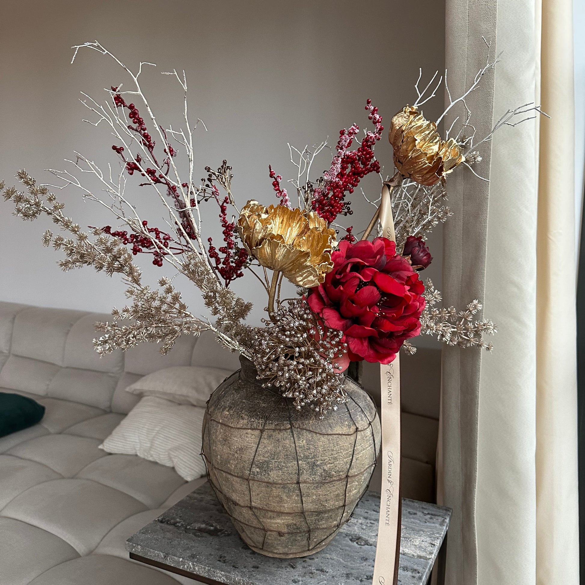 Rijk winterboeket van kunstbloemen met rode pioen, gouden papaver en groene bladeren – stijlvolle decoratie voor woonkamer, eettafel of kerstinterieur.