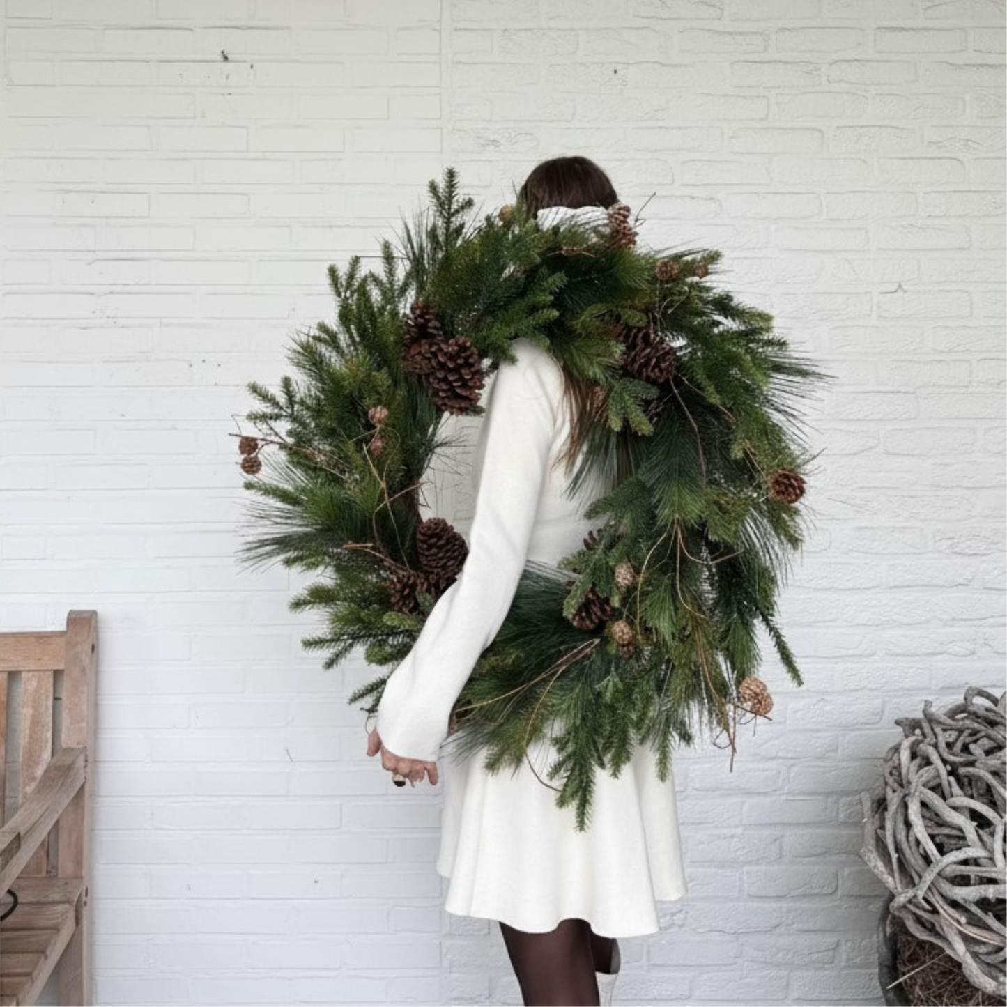 Luxe kunstkerstkrans met dennenappels en groen, stijlvol opgehangen aan een moderne voordeur — perfecte duurzame kerstdecoratie voor buiten.