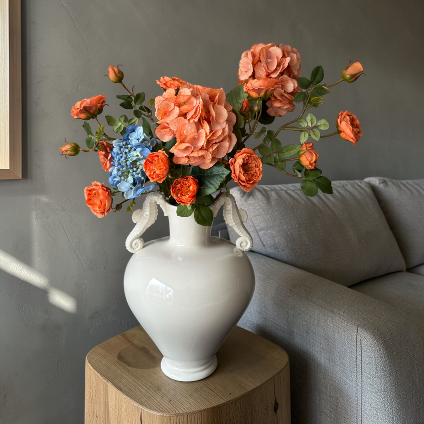 Luxury Burnt Apricot & Blue Mini Bouquet with silk orange garden roses and blue hydrangeas arranged in a white vase on a side table