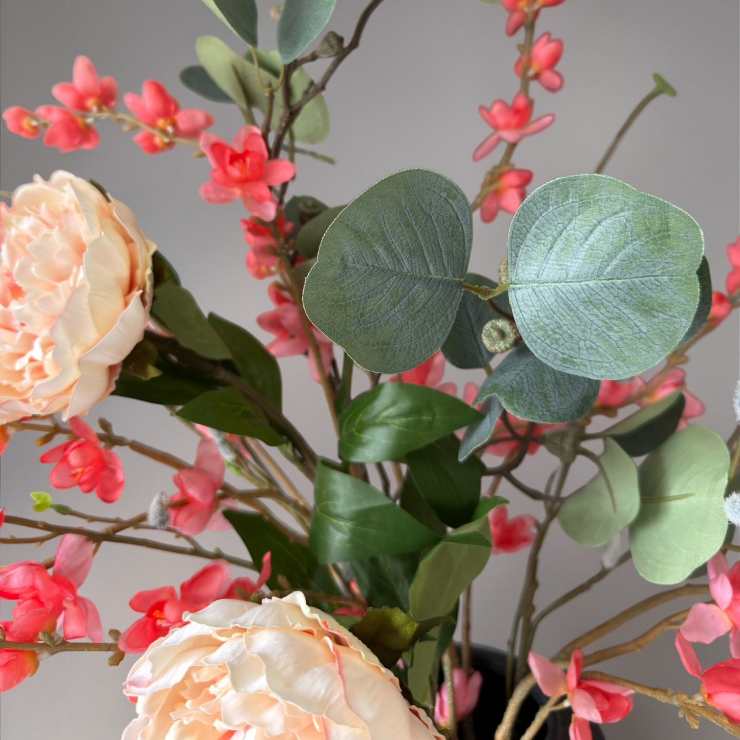 Peach Bloom Boeket met hoogwaardige zijden bloemen in perzik, koraal en zachte groentinten gestyled in een hoge zwarte vaas voor stijlvolle woondecoratie en interieur styling.