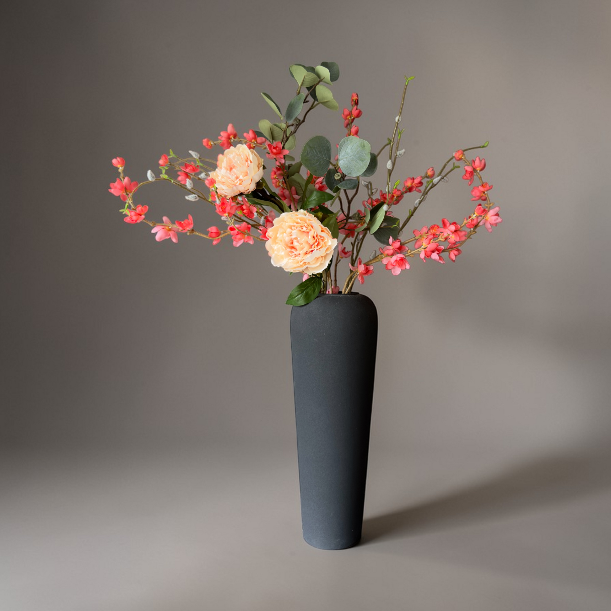 Luxe Peach Bloom zijden bloemen boeket met perzik tuinrozen, koraal bloesem en eucalyptus in een moderne zwarte vaas voor tijdloze woondecoratie.