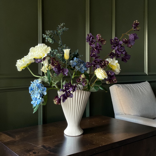 Luxe zijden bloemen boeket in pruim, geel en blauwe tinten met bloesemtakken en hortensia in een witte vaas voor tijdloze woondecoratie.