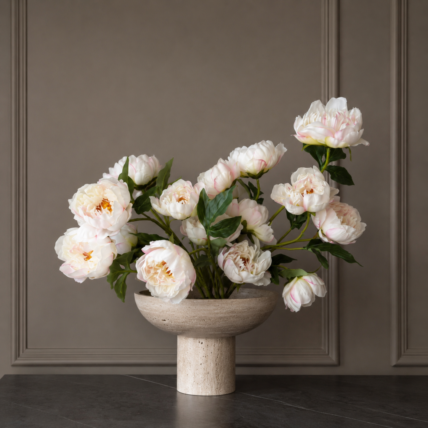 Arrangement van real touch crème roze pioenrozen in een sculpturale stenen vaas