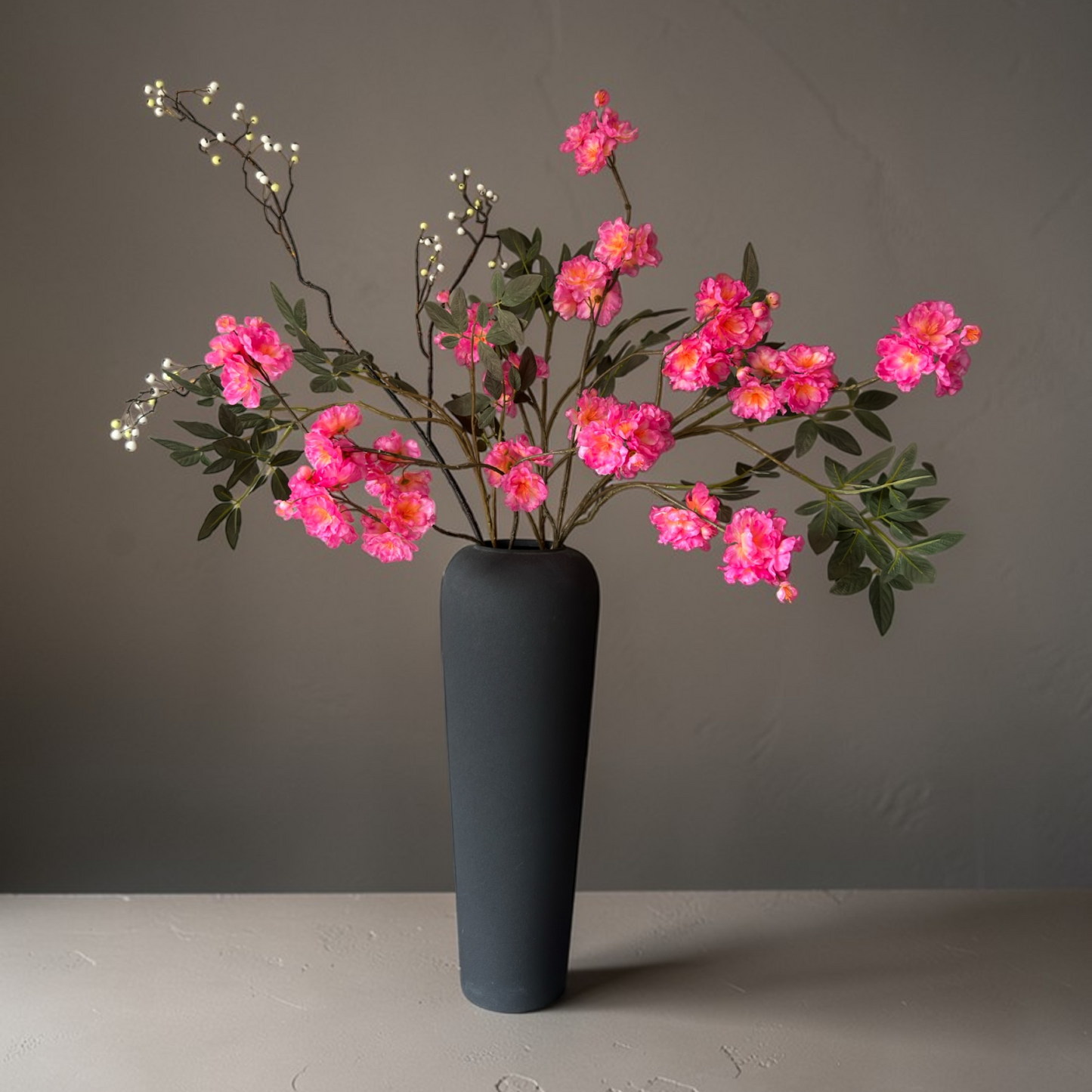 Luxe zijden bloemen boeket met roze bloesem en takken in een moderne zwarte vaas voor woondecoratie en interieur styling.