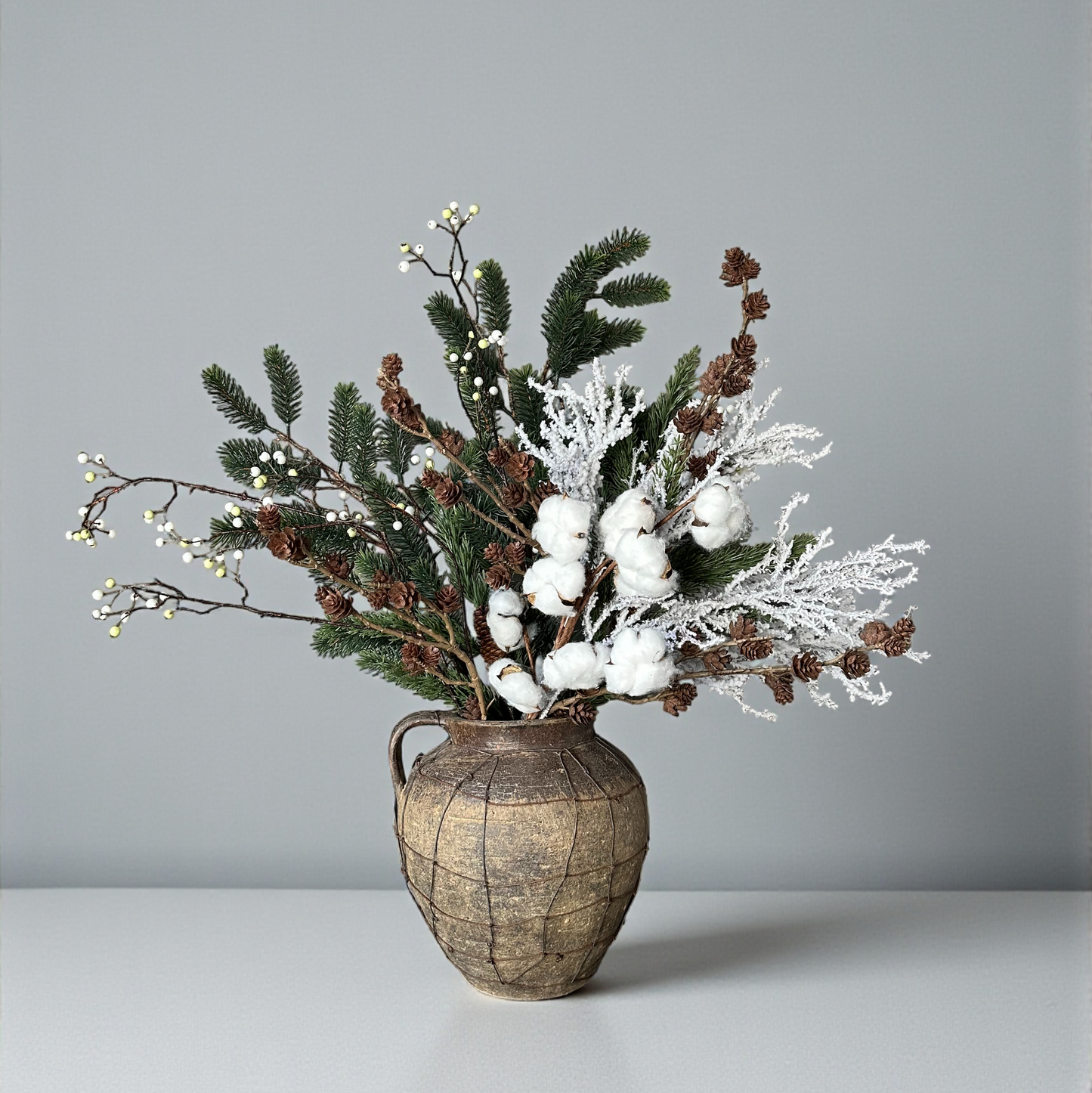 Luxe winterboeket met katoentakken, berijpte dennen en witte bessen in aardetint vaas. Handgemaakt kunstbloemenarrangement van Jardin Enchanté — stijlvolle winterdecoratie voor woonkamer of tafel.